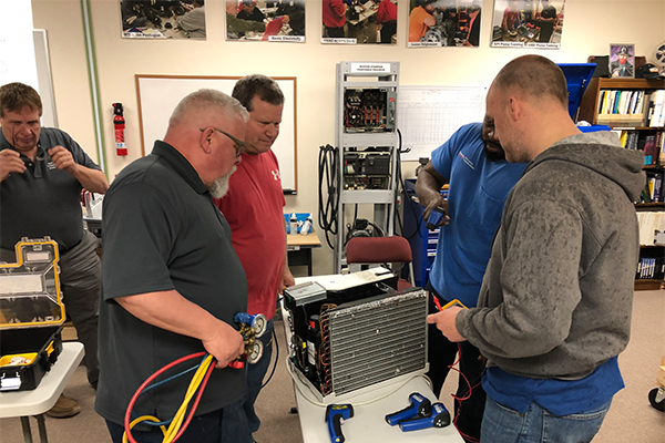 Students standing around an air conditioner unit problem solving