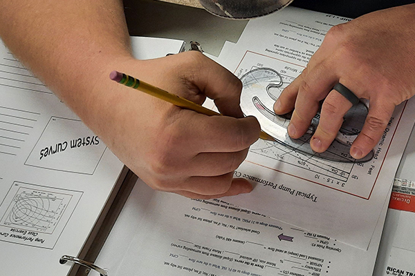 Student using a french curve to develop a pump performance curve