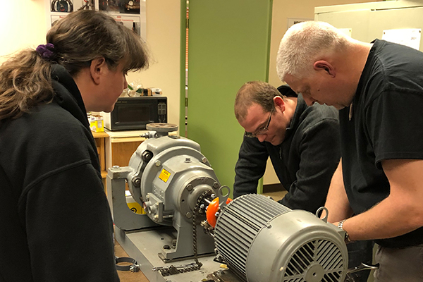 Students adding shims to a piece of equipment