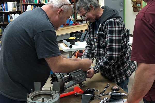 Two students removing the cover of a piece of equipment to troubleshoot it